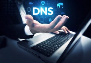 hacked? DNS hovering above a man's hand with his other hand on a laptop keyboard